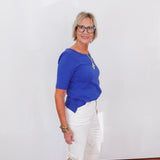Woman wearing a blue top and white pants against a white background