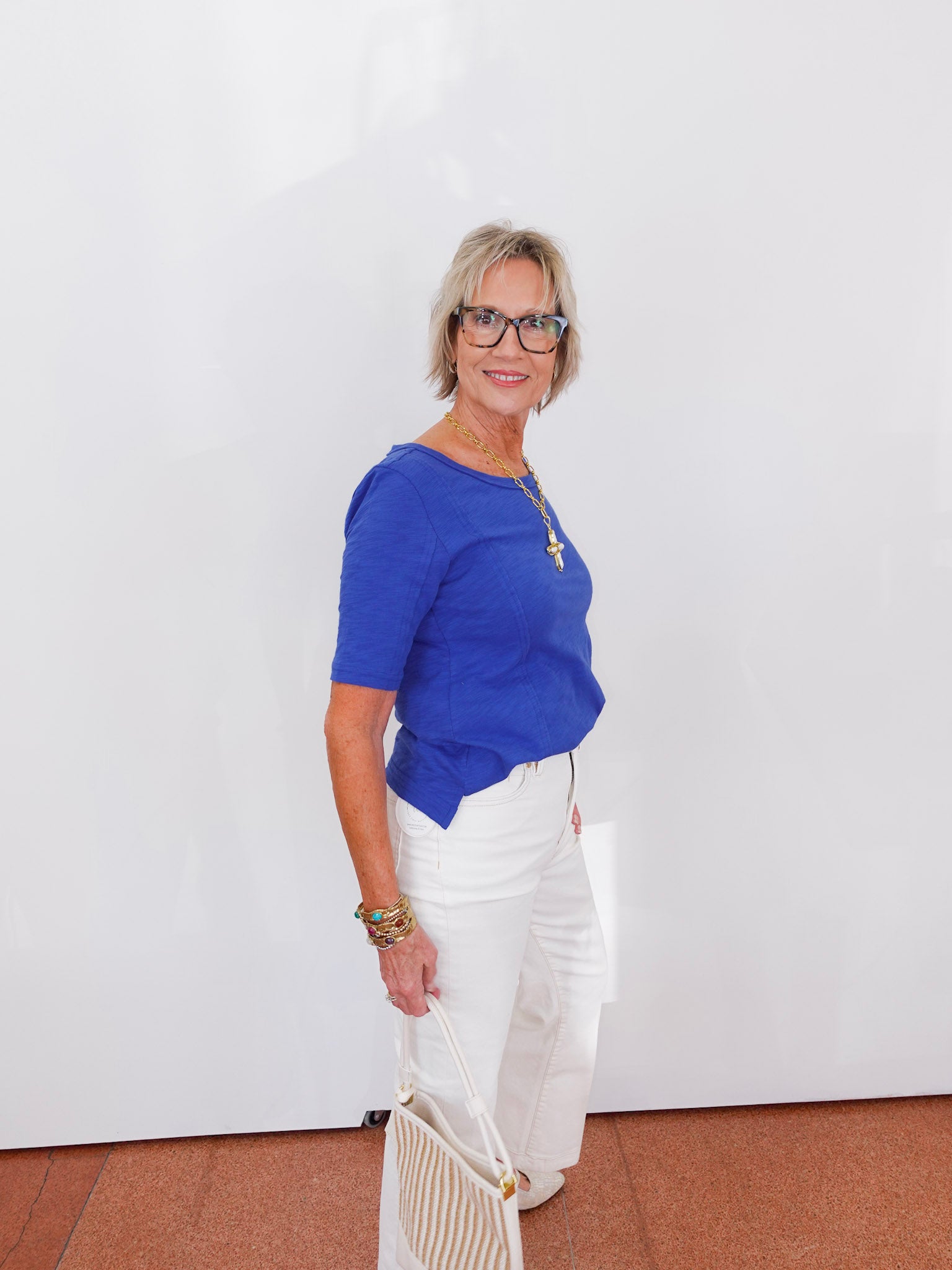 Woman wearing a blue top and white pants against a white background