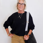 woman wearing a black sweatshirt that has black sequin bats on it