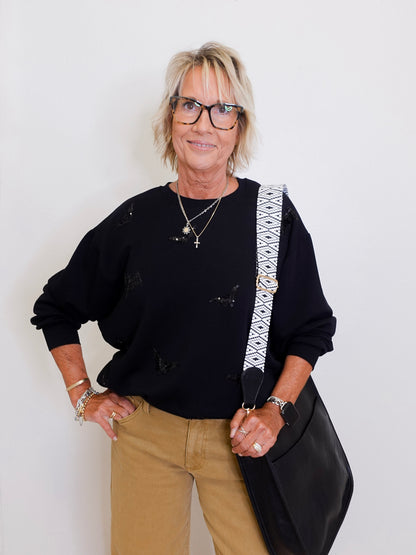 woman wearing a black sweatshirt that has black sequin bats on it