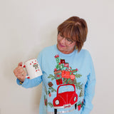 woman wearing a blue knit top against a white background. 