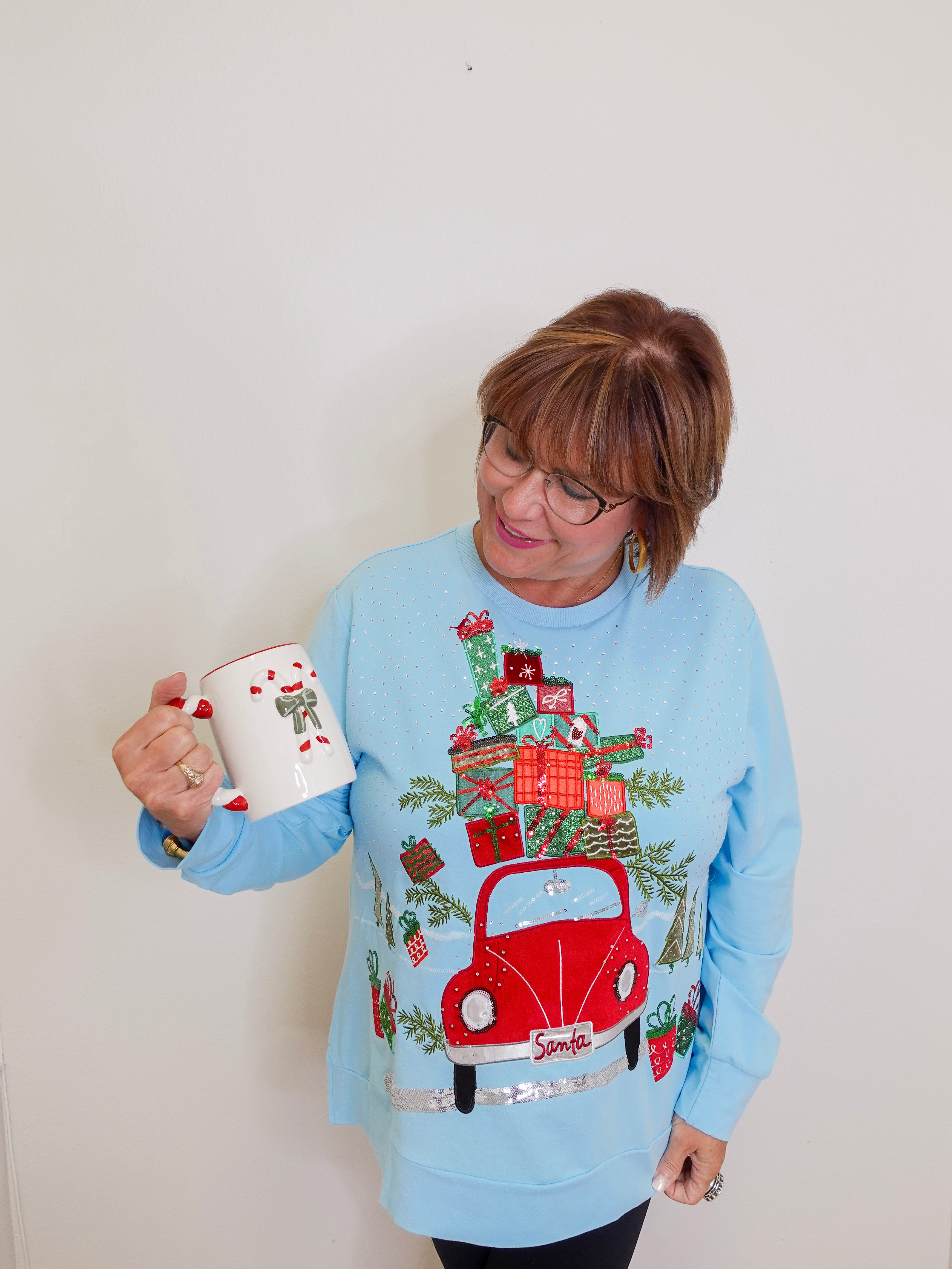 woman wearing a blue knit top against a white background. 