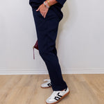 Person wearing navy tracksuit and white sneakers on a light wooden floor.