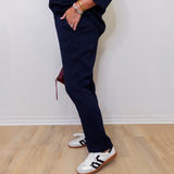 Person wearing navy tracksuit and white sneakers on a light wooden floor.