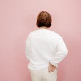 Person wearing a white shirt and beige pants against a pink background