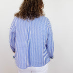 Person wearing a blue and white striped shirt with a plain background