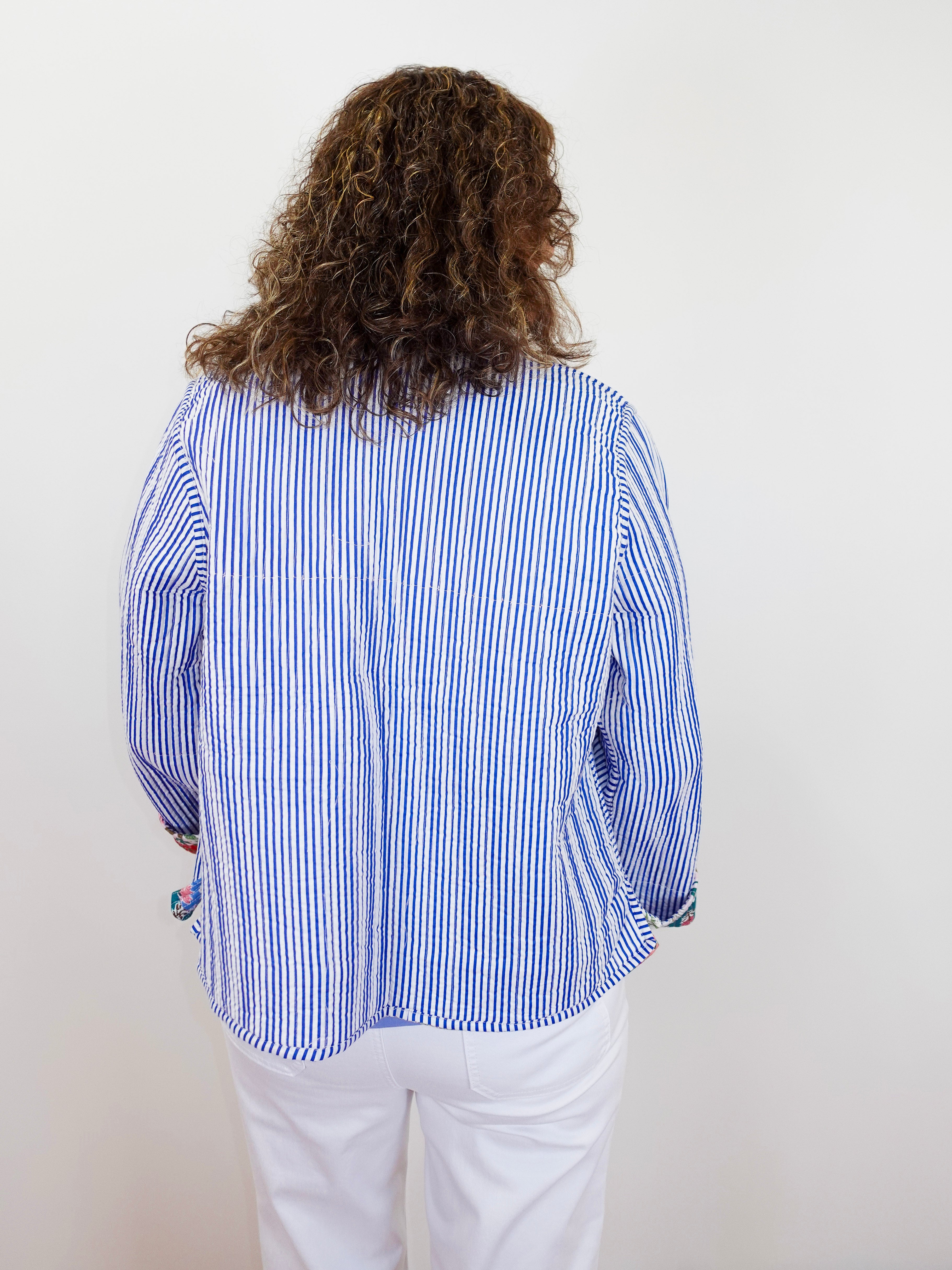 Person wearing a blue and white striped shirt with a plain background