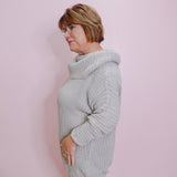 Woman wearing a light gray sweater against a pink wall