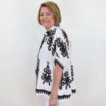 Woman wearing a black and white patterned top against a white background