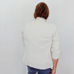 Person wearing a light-colored sweater and blue jeans, holding a brown bag against a white background