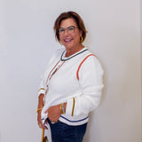 Woman wearing a white sweater with colorful accents against a plain background