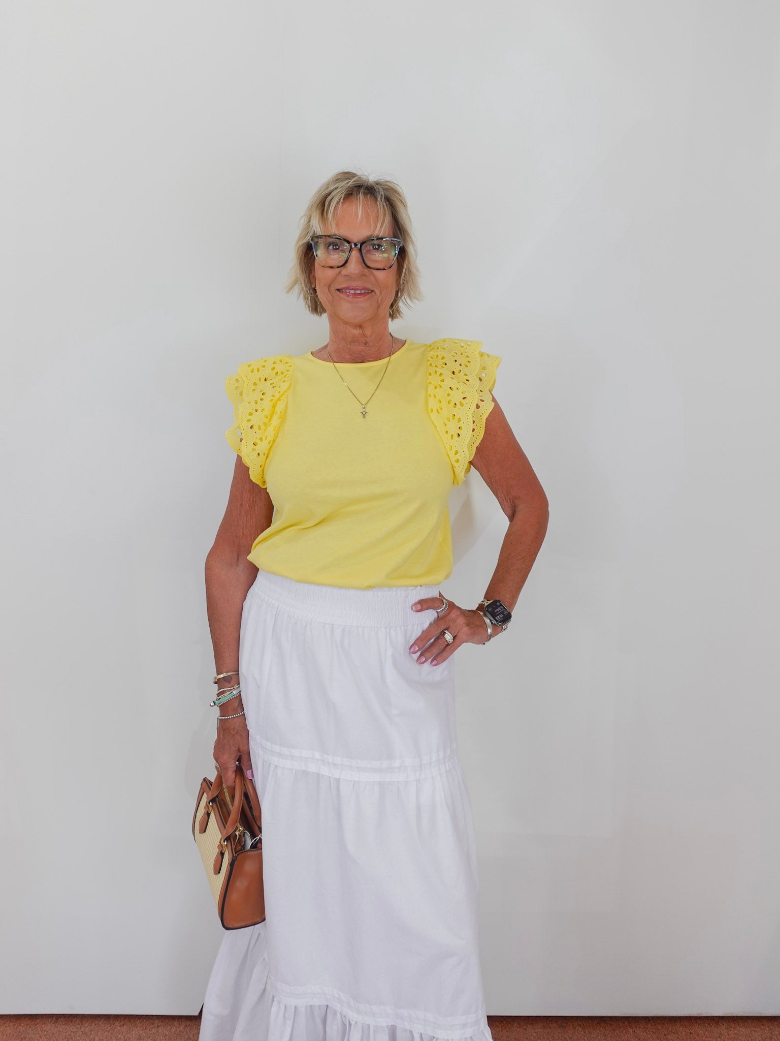 Woman wearing a yellow top and white skirt against a plain background