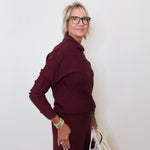 Woman wearing a burgundy outfit with a white wall background