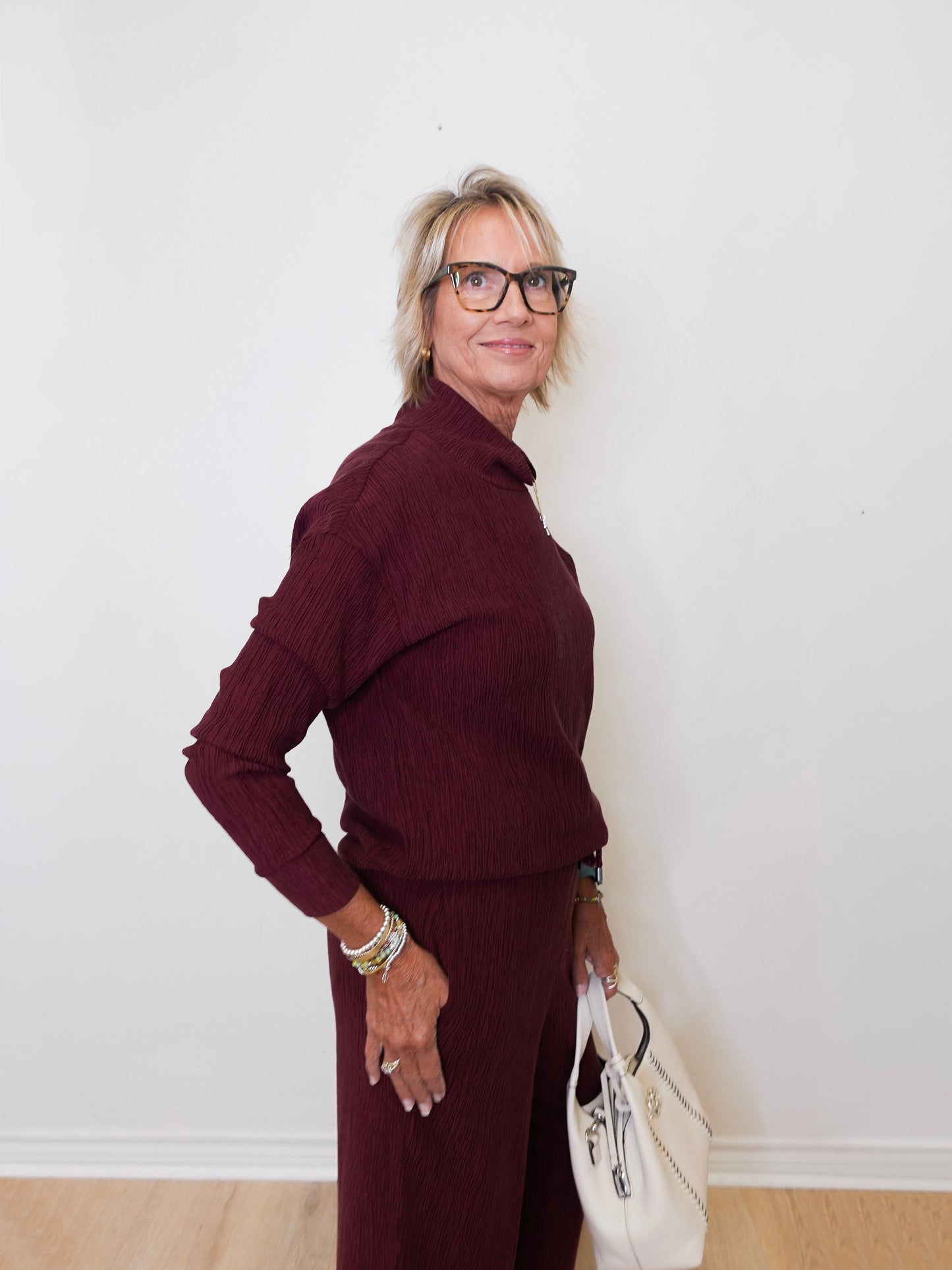 Woman wearing a burgundy outfit with a white wall background