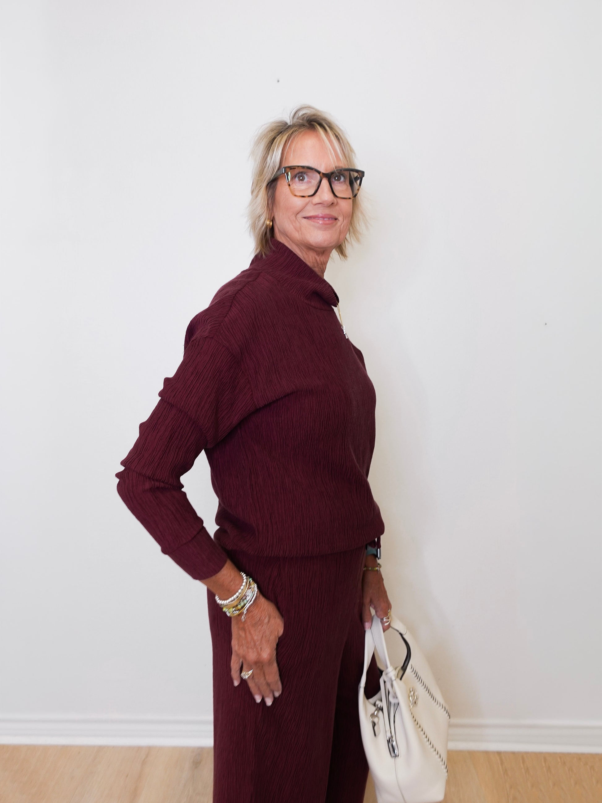 Woman wearing a burgundy outfit with a white wall background