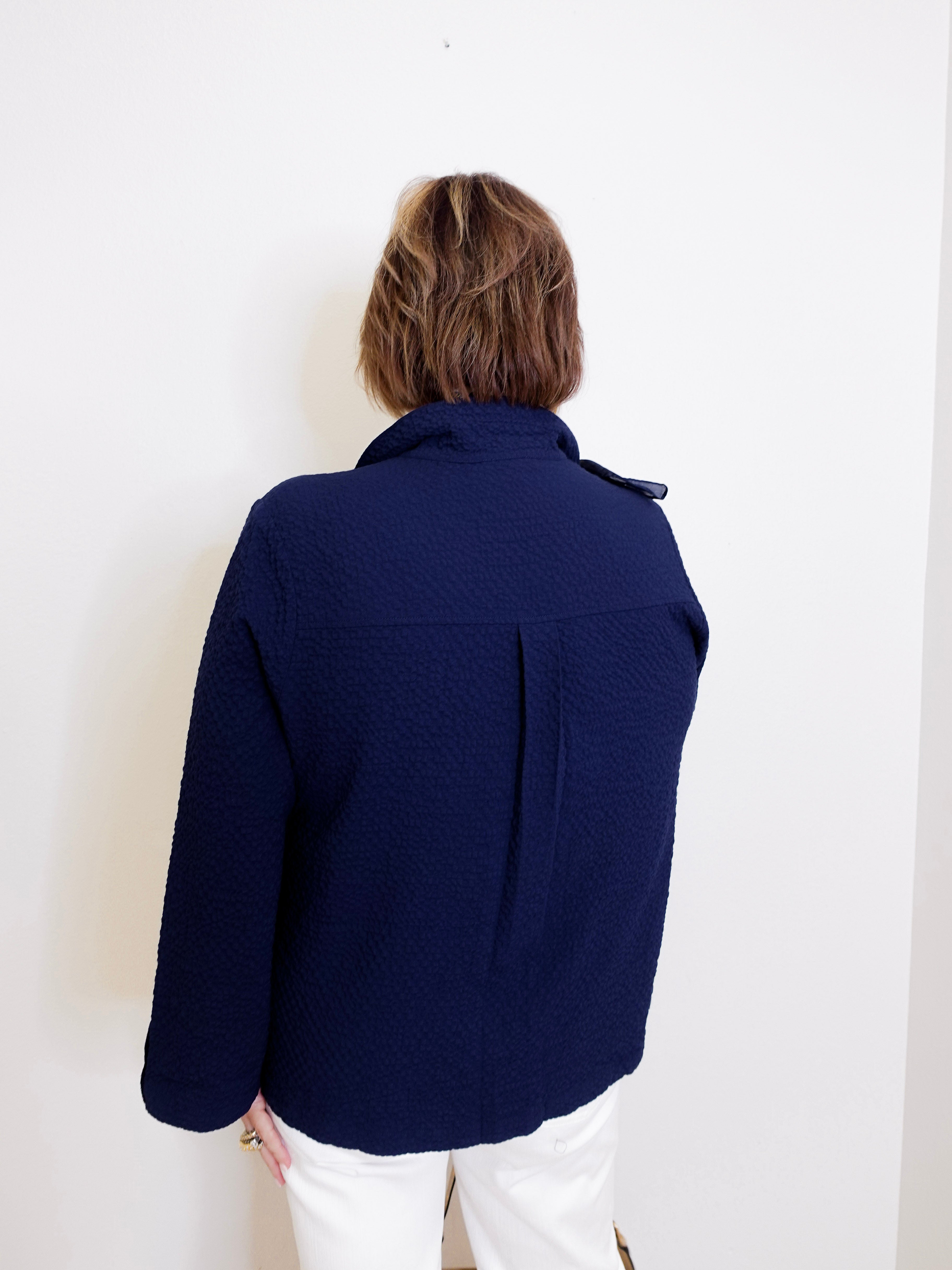 Person wearing a navy blue jacket against a white background