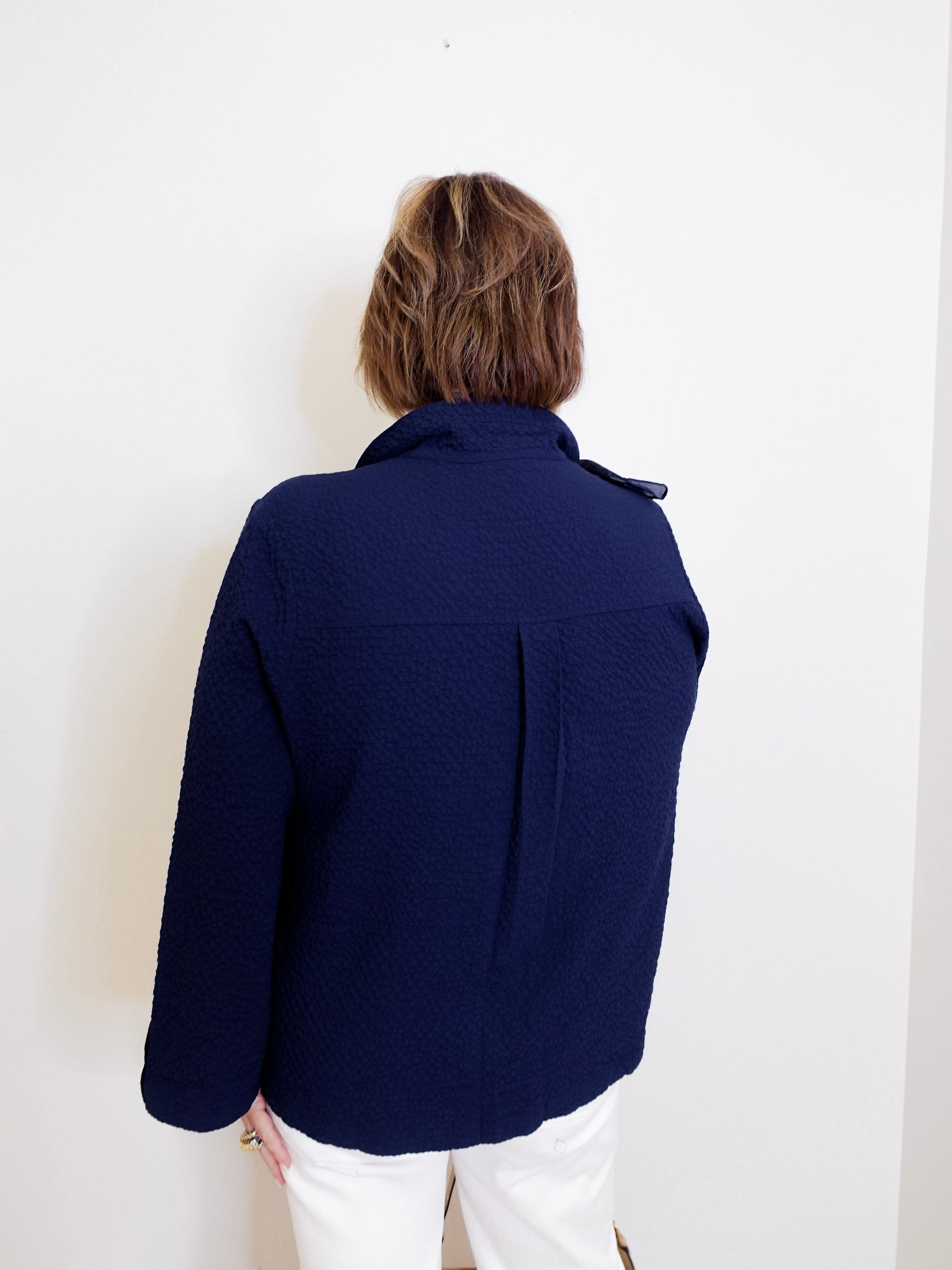 Person wearing a navy blue jacket against a white background