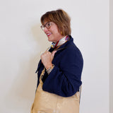 Woman holding a beige handbag against a plain background