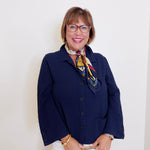 Woman wearing a navy blue jacket with a colorful scarf against a white background