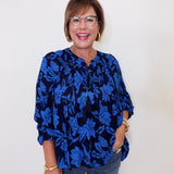 Woman wearing a blue floral blouse against a white background