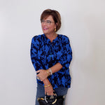 Woman wearing a blue floral blouse against a white wall