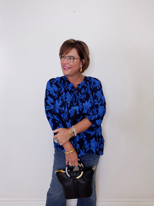 Woman wearing a blue floral blouse against a white wall
