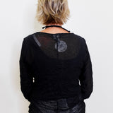 Person wearing a black textured top against a white background