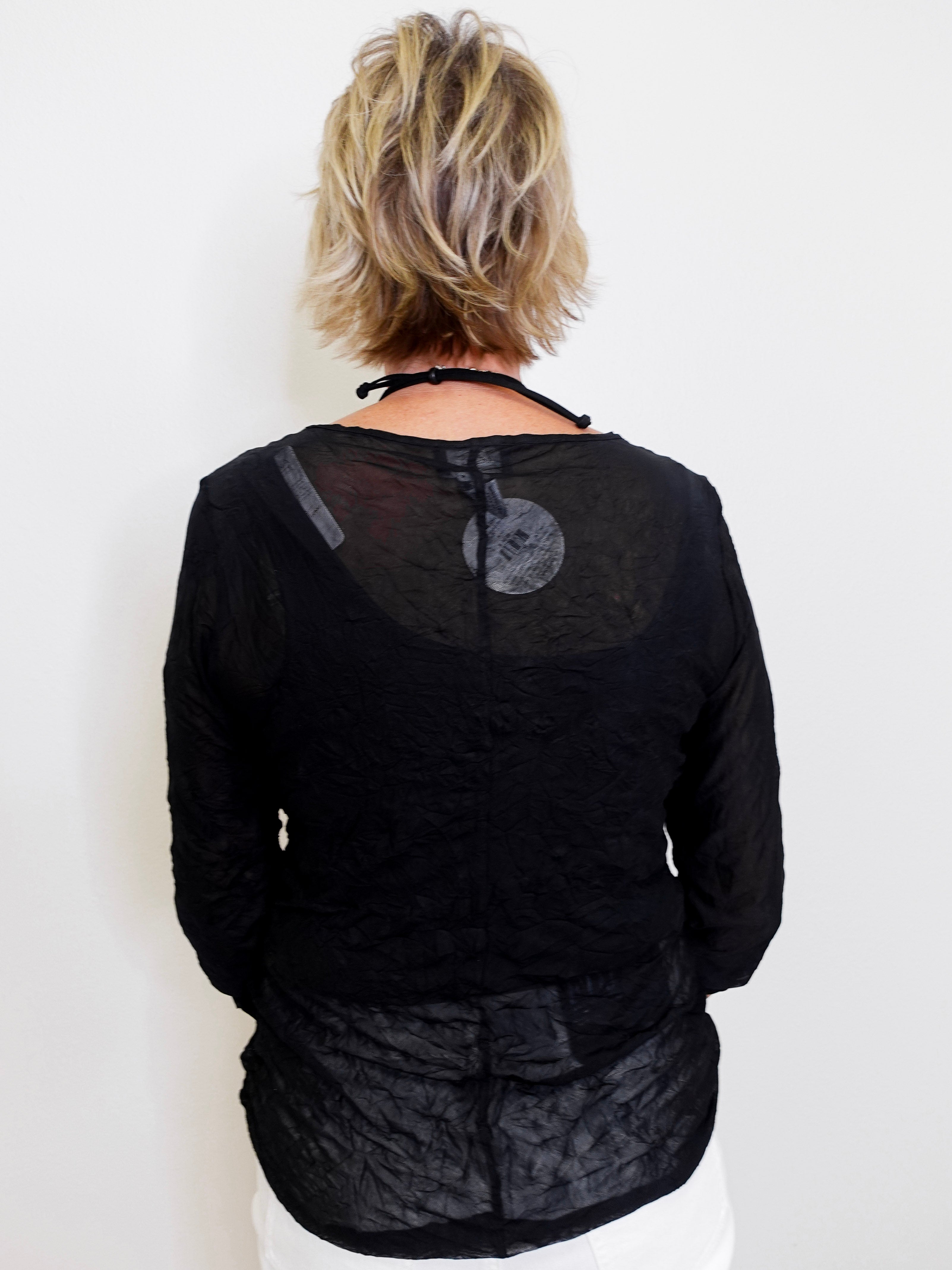 Person wearing a black textured top against a white background