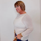 Woman wearing a light gray sweater and dark blue jeans against a white background