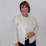 Woman wearing a light-colored jacket and dark pants against a white background