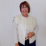 Woman wearing a light-colored jacket and dark pants against a white background