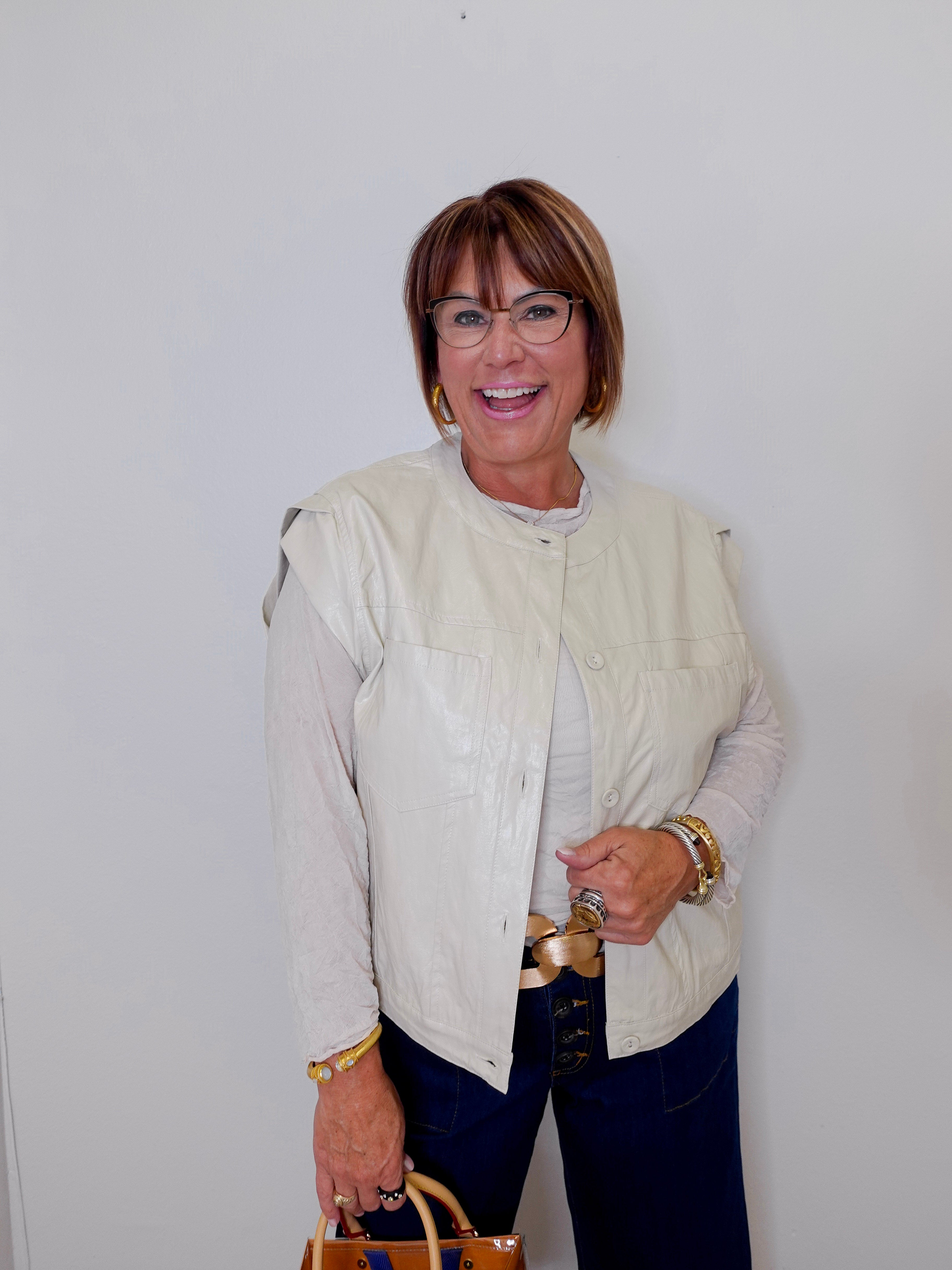 Woman wearing a light-colored jacket and dark pants against a white background
