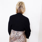Person wearing a black sweater and leopard print skirt against a white background