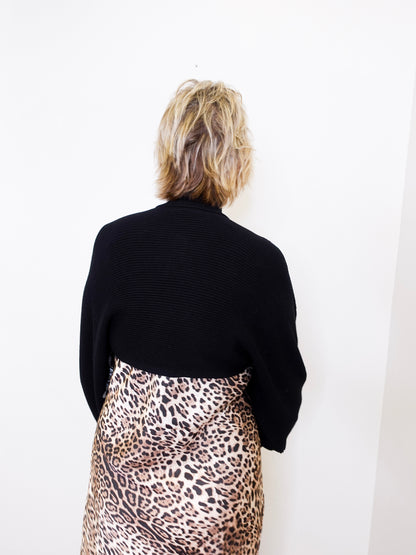 Person wearing a black sweater and leopard print skirt against a white background