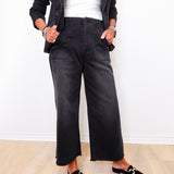 Person wearing black wide-leg pants and black loafers on a light wooden floor.