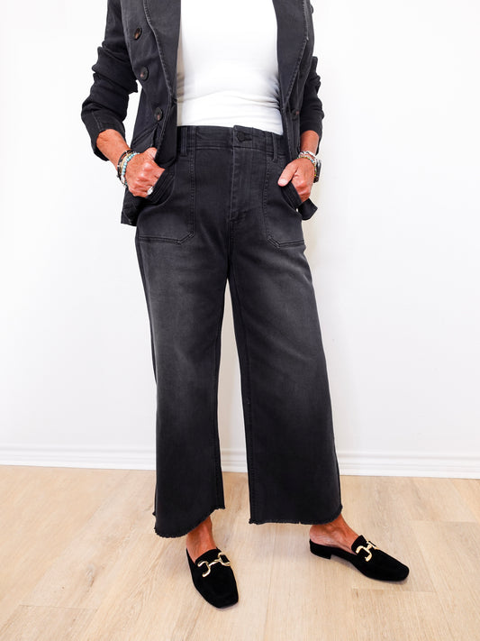 Person wearing black wide-leg pants and black loafers on a light wooden floor.