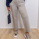 Woman wearing a grey wide leg cropped pant in front a white background. 