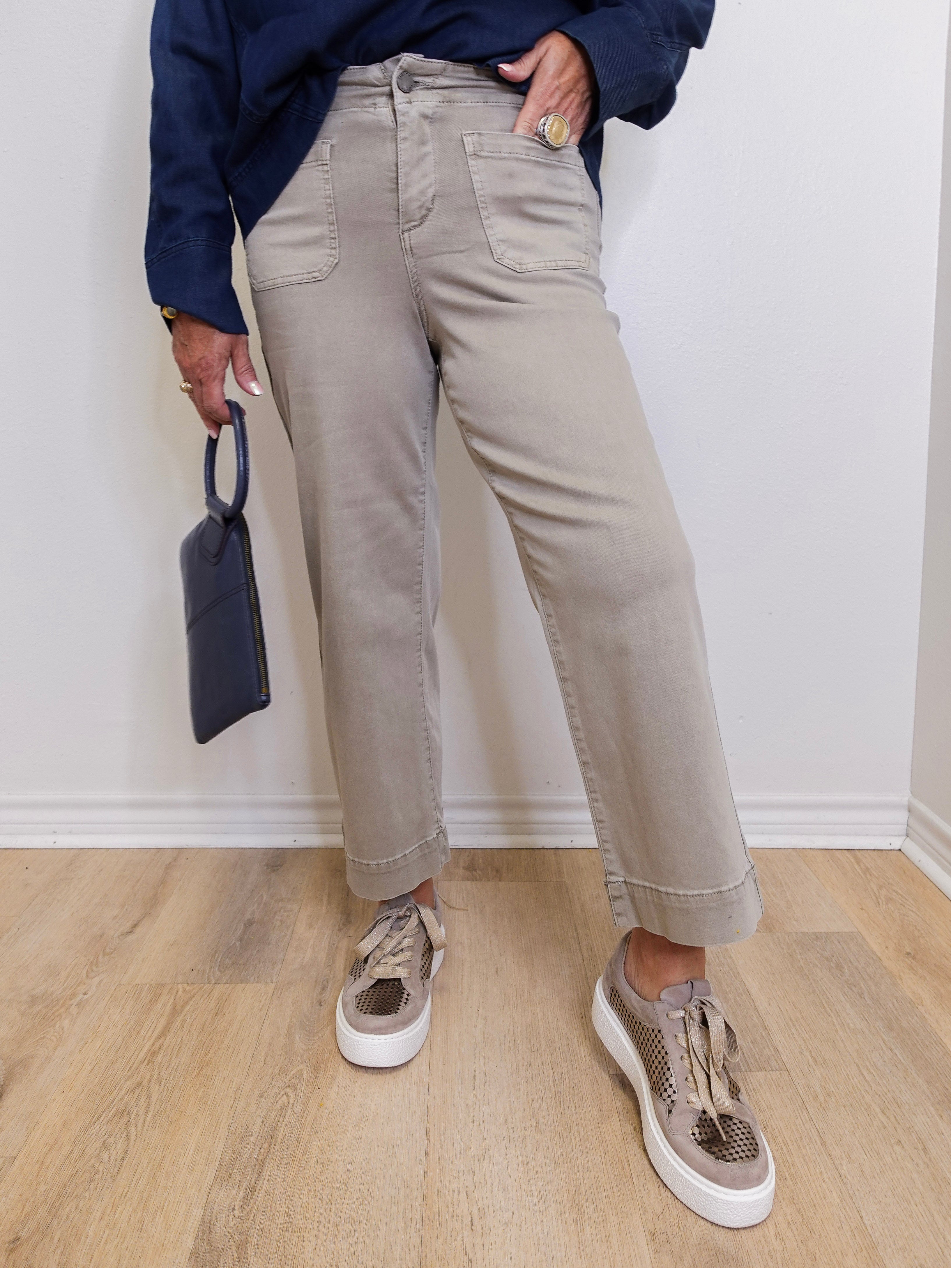 Woman wearing a grey wide leg cropped pant in front a white background. 