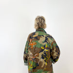 Person wearing a colorful camouflage jacket on a white background