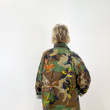 Person wearing a colorful camouflage jacket on a white background