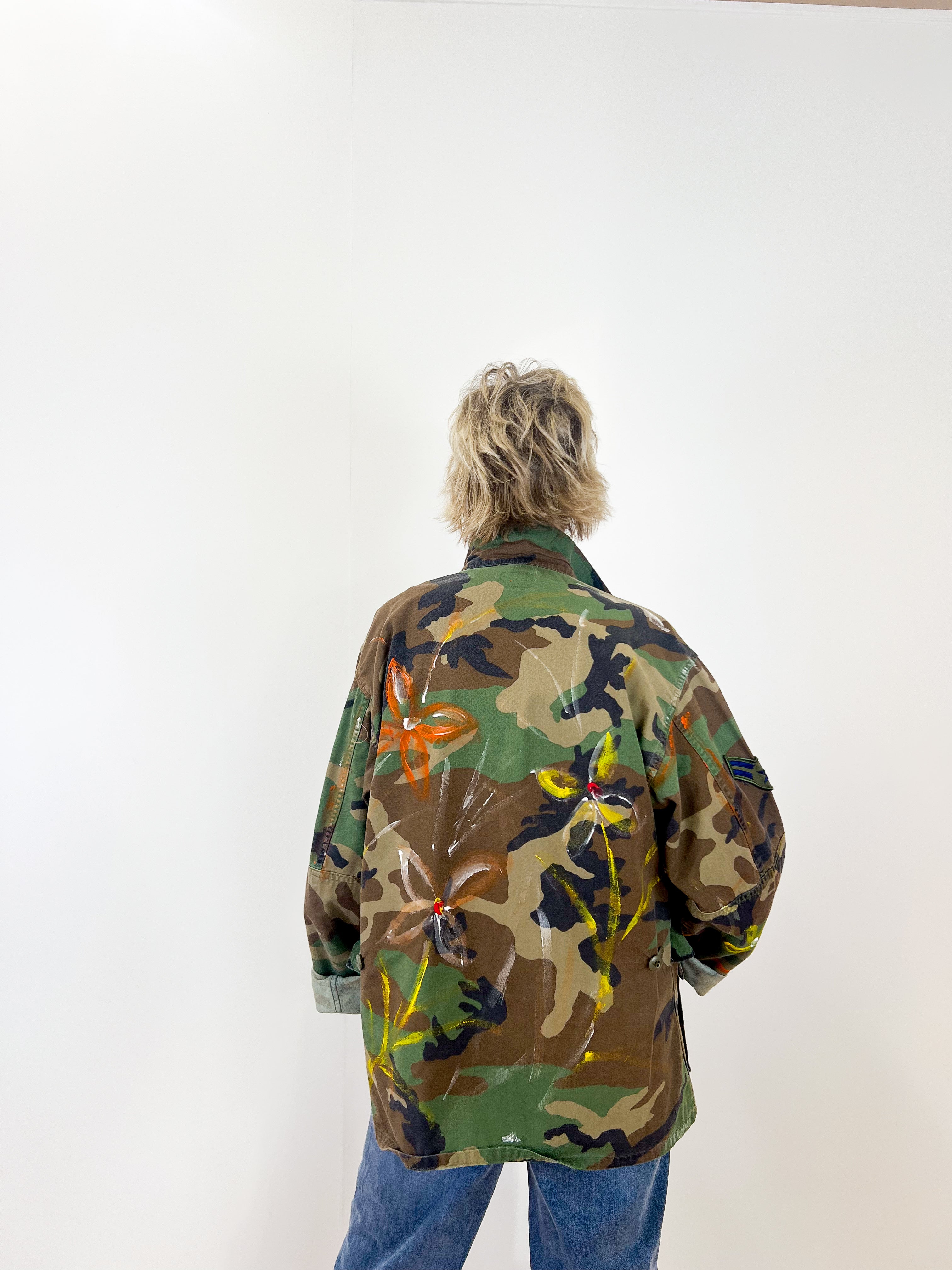 Person wearing a colorful camouflage jacket on a white background