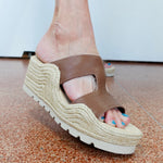 Brown wedge sandal on a foot with a white background