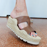 Brown wedge sandal on a foot with a white background