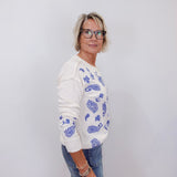 woman styled in johnny was daniela patchwork thermal long sleeve top with blue embroidery and jeans