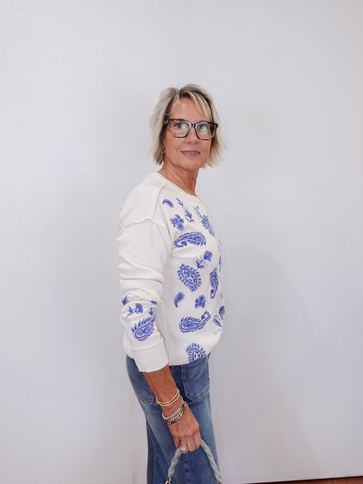 woman styled in johnny was daniela patchwork thermal long sleeve top with blue embroidery and jeans