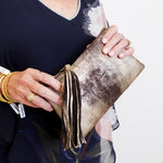 Person holding a gold clutch with a white background