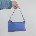 Blue handbag held by a person against a white background