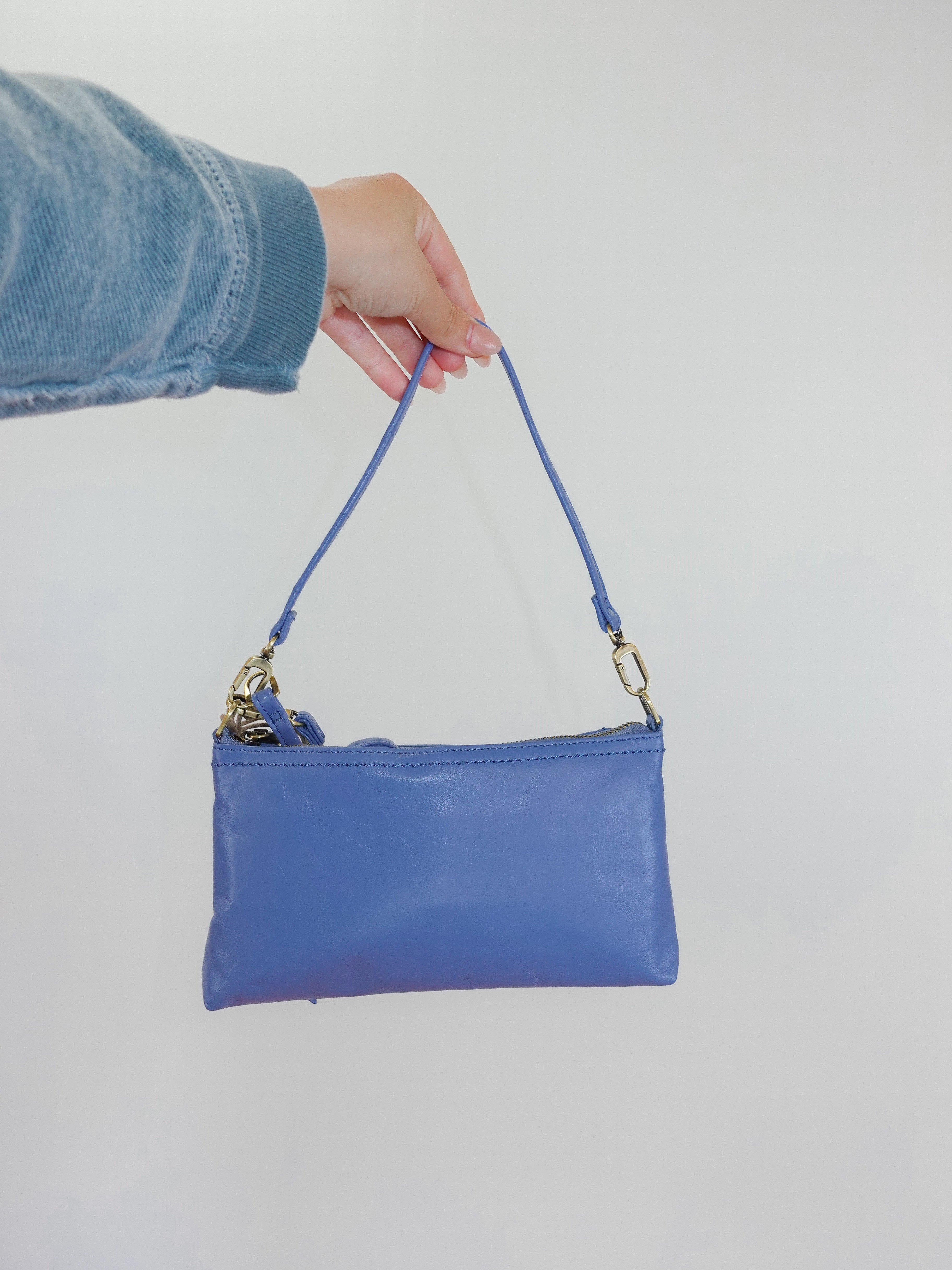 Blue handbag held by a person against a white background
