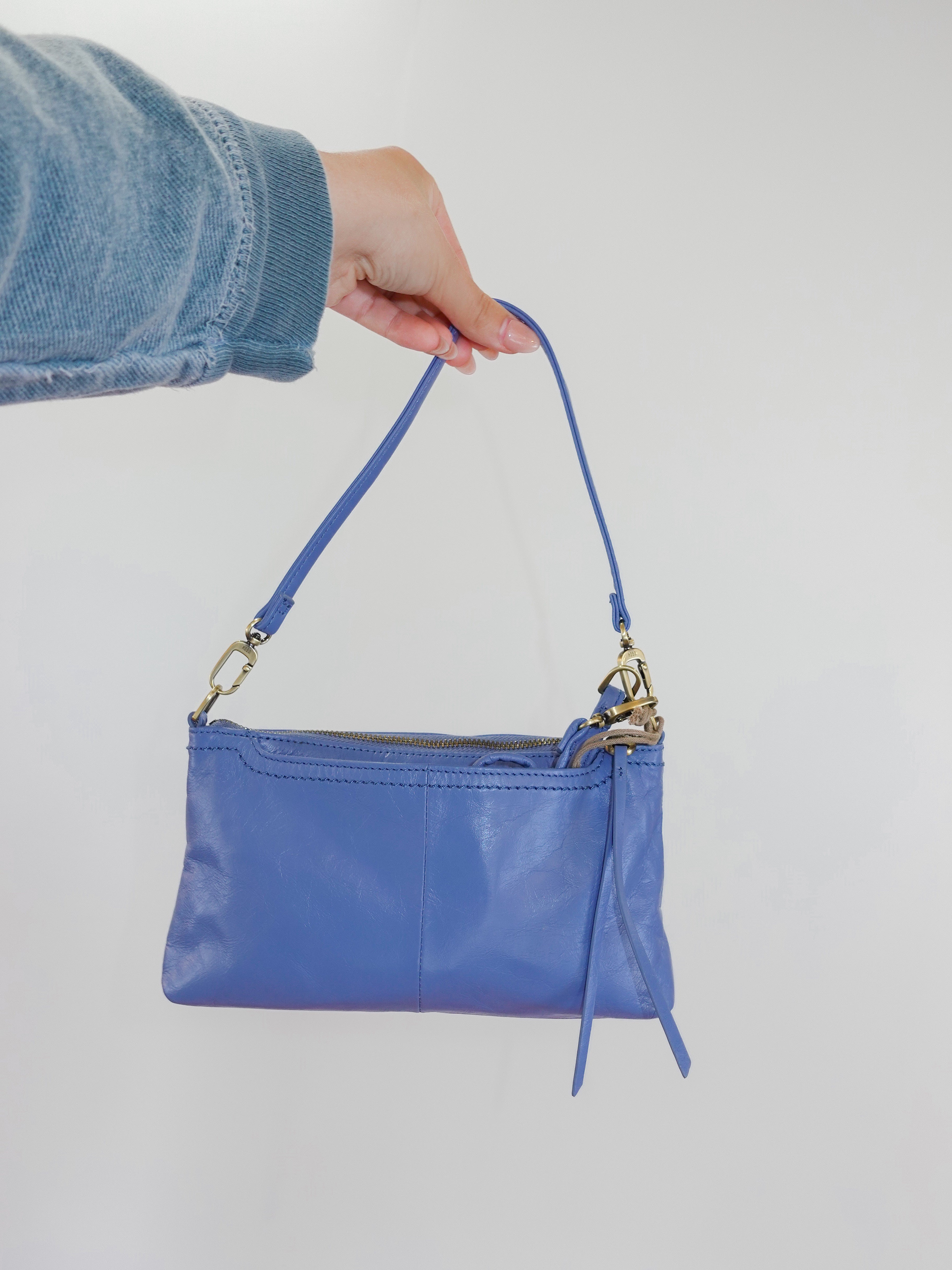 Blue handbag held by a person against a plain background