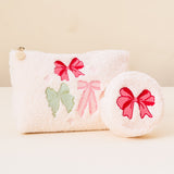 Two white pouches with colorful bows on a beige background